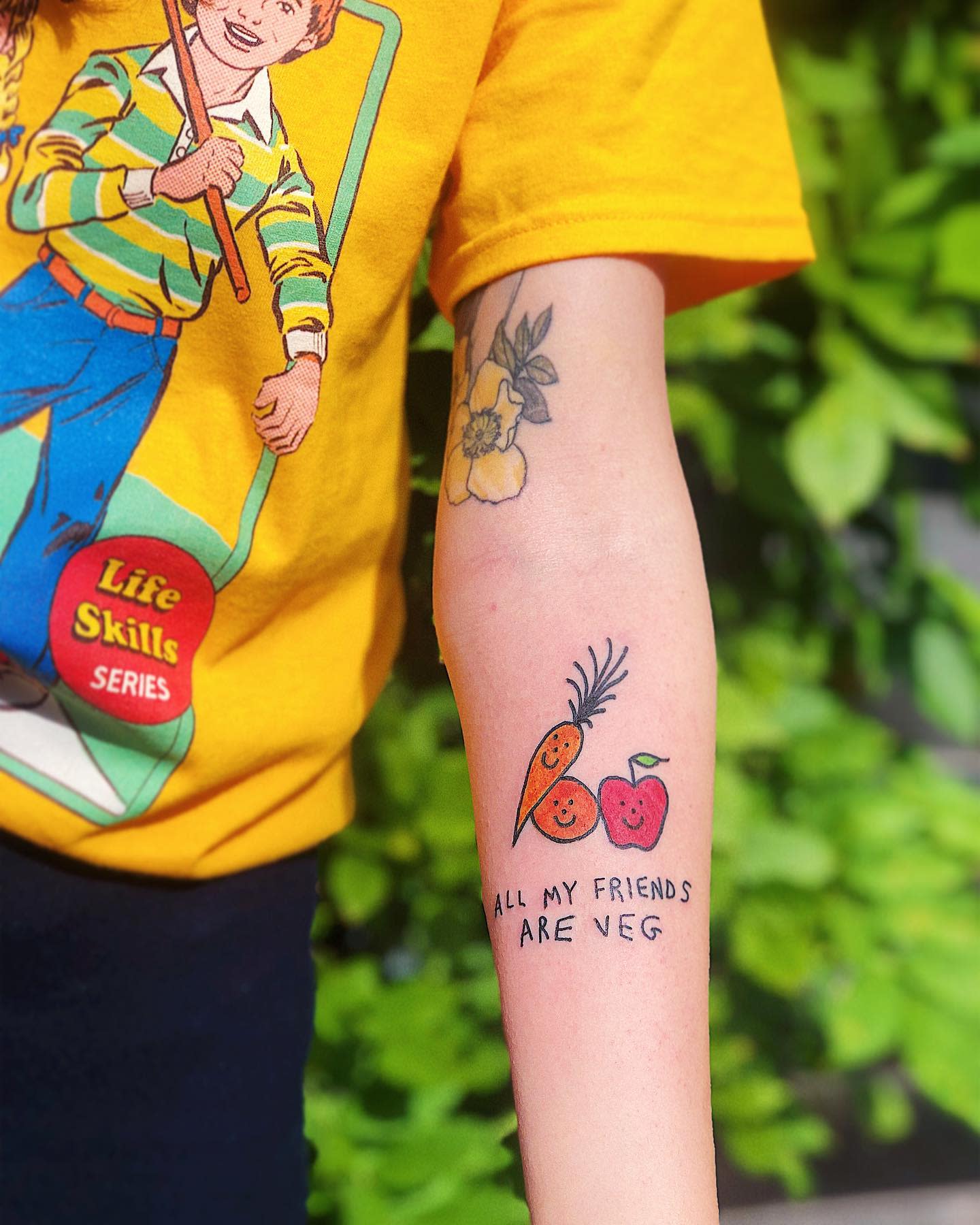 Arm with a tattoo of a carrot, apple, and words "All my friends are veg"