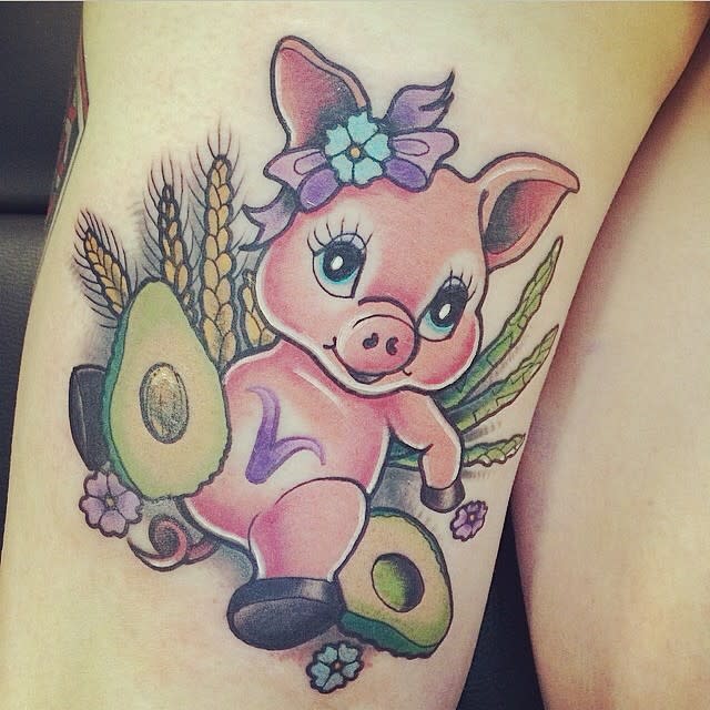 Colorful tattoo of a cute piglet with flowers, avocado, and wheat on a leg