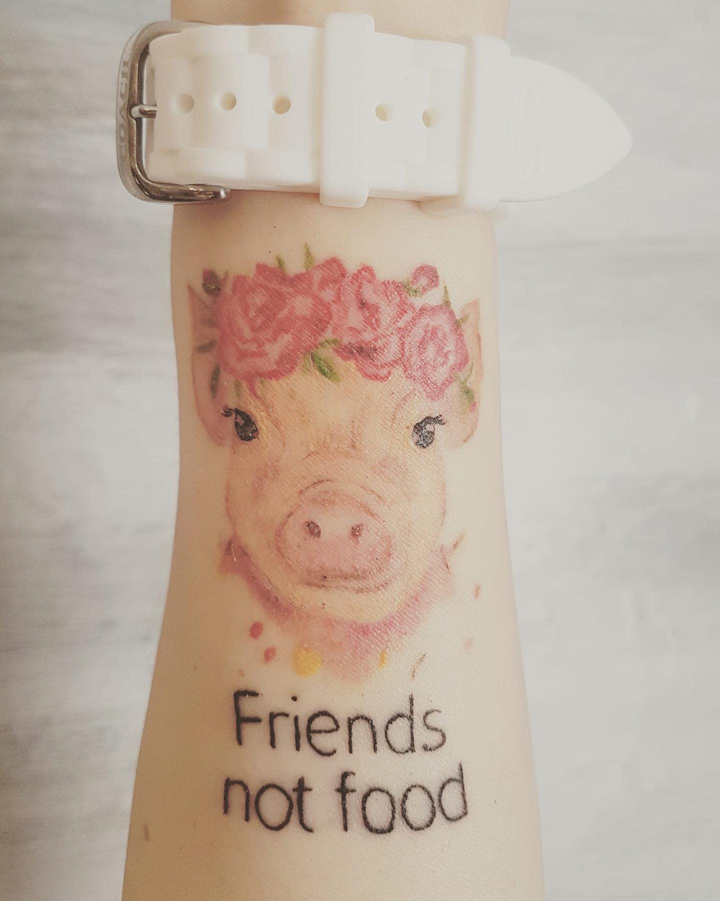 Tattoo of a pig wearing a flower crown with the phrase "Friends not food" below it