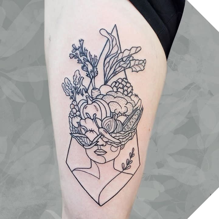 Tattoo of a woman's face with flowers and vegetables on her head in a modern line art style