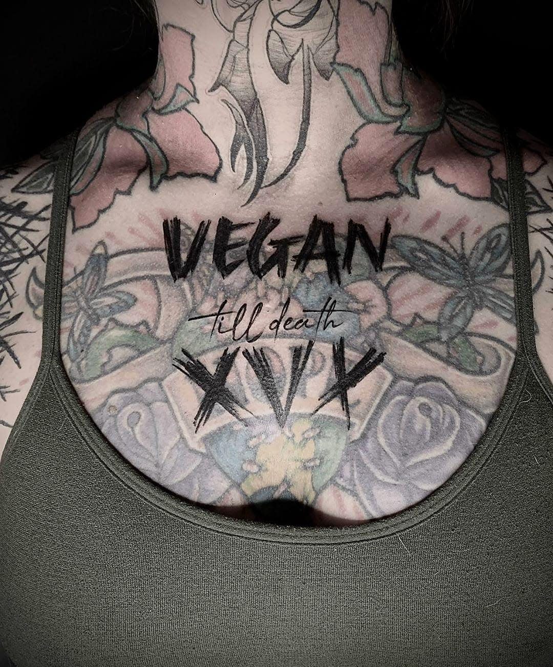 Chest tattoo with flowers and the words "VEGAN till death XVX"