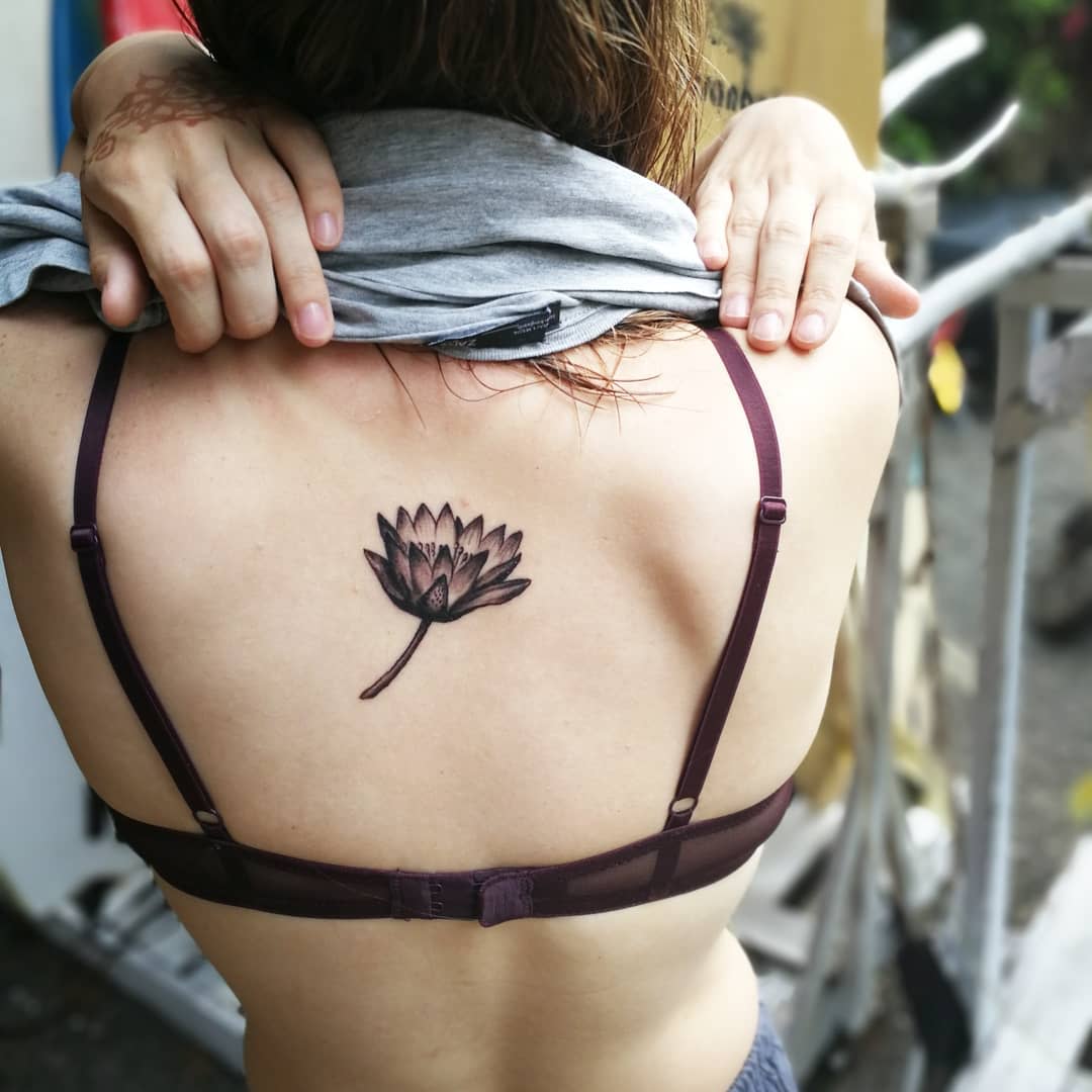 Detailed water lily flower tattoo on the upper back