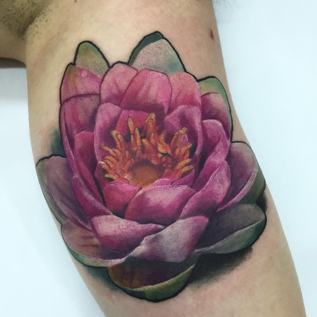 A realistic water lily tattoo on the upper arm, featuring rich pink petals and a detailed yellow-orange center, with subtle shading and highlights for depth