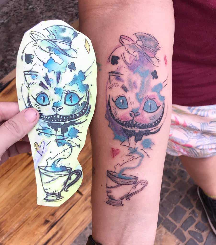 A watercolor-style Cheshire Cat tattoo on an arm