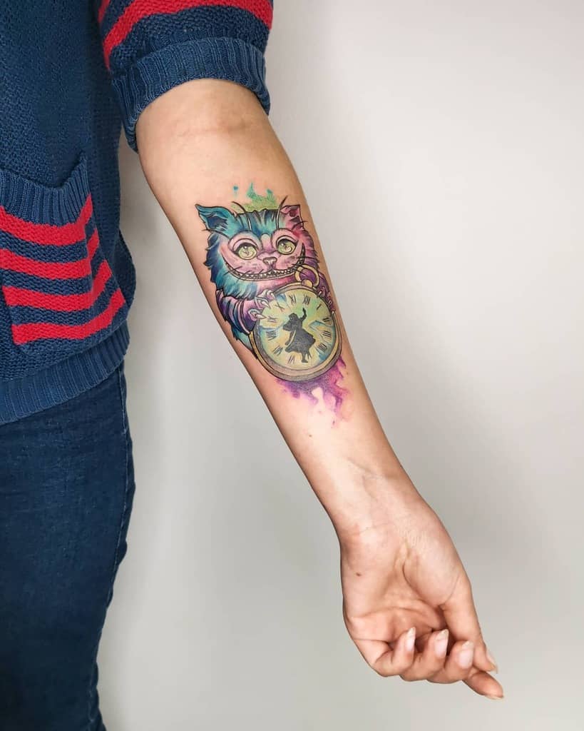 Colorful Cheshire Cat tattoo holding a clock on a forearm
