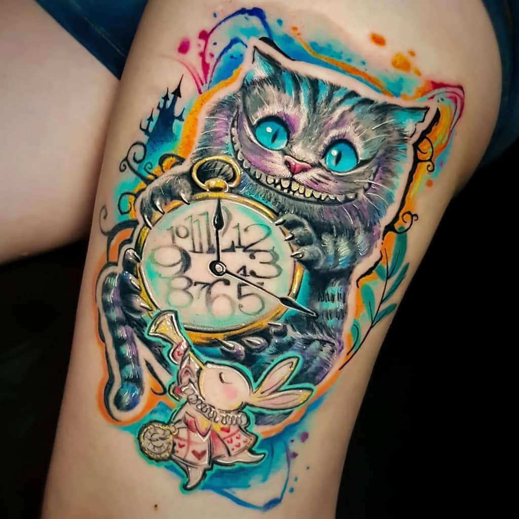 Colorful tattoo of the Cheshire Cat holding a clock, with a rabbit at the bottom