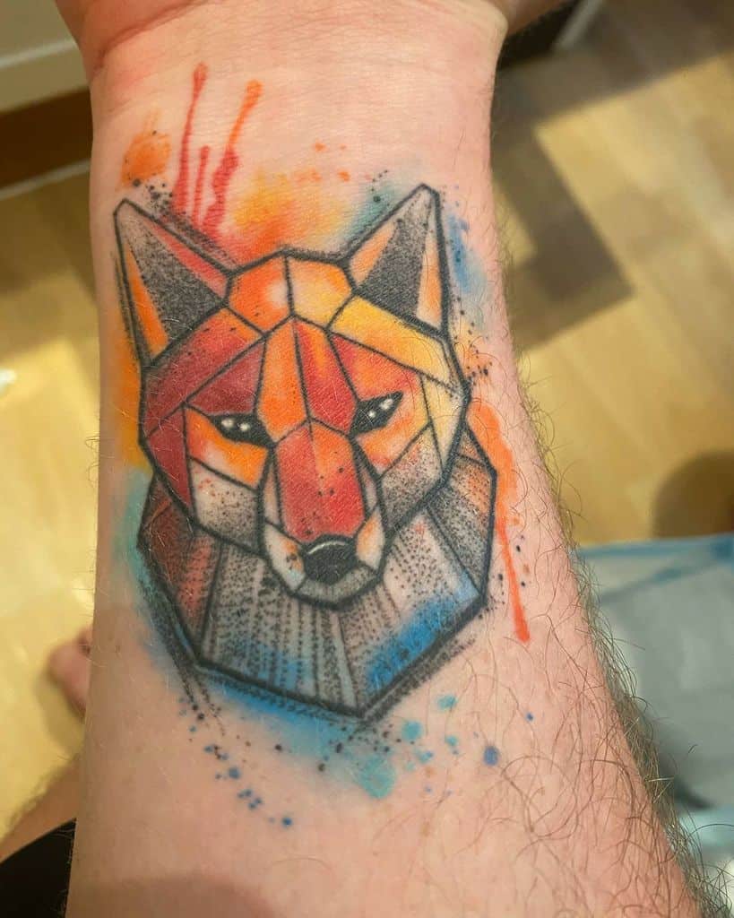 Geometric fox tattoo with vibrant watercolor splashes on a forearm