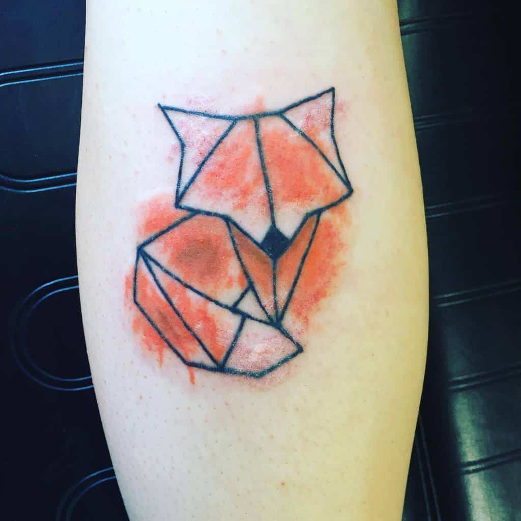 A stunning geometric fox tattoo with watercolor shading on a person's arm