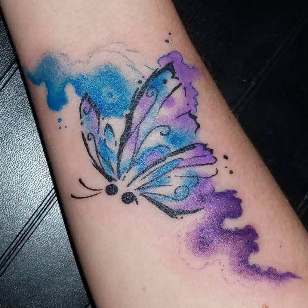 A watercolor butterfly tattoo with blue and purple hues and a semicolon body, symbolizing hope and mental health awareness
