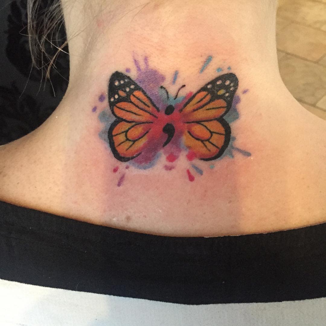 A vibrant orange and purple watercolor butterfly tattoo with a semicolon body on the back of the neck, symbolizing resilience and mental health awareness