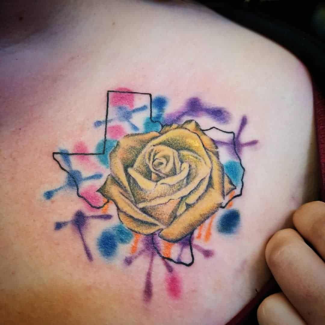 Tattoo of a rose over a Texas state outline with colorful splashes on the upper chest