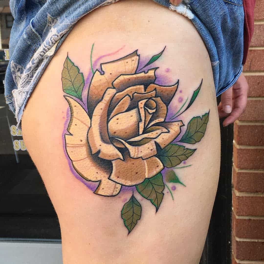A detailed yellow rose tattoo with green leaves and light purple accents on the upper thigh