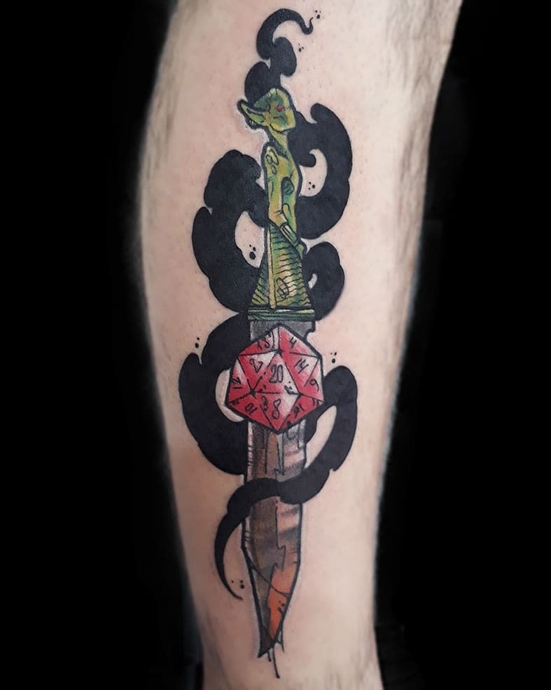 Unique Dungeons & Dragons tattoo of a dagger with a red d20 die, eerie black smoke, and a sinister goblin-shaped hilt design