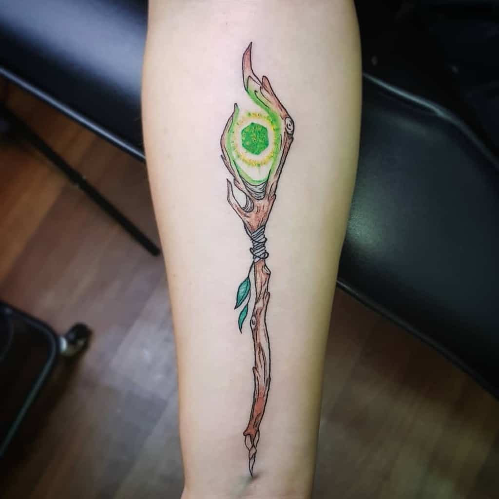 Elegant Dungeons & Dragons tattoo of a wooden staff with a glowing green gem, wrapped in vines, symbolizing nature-based magic