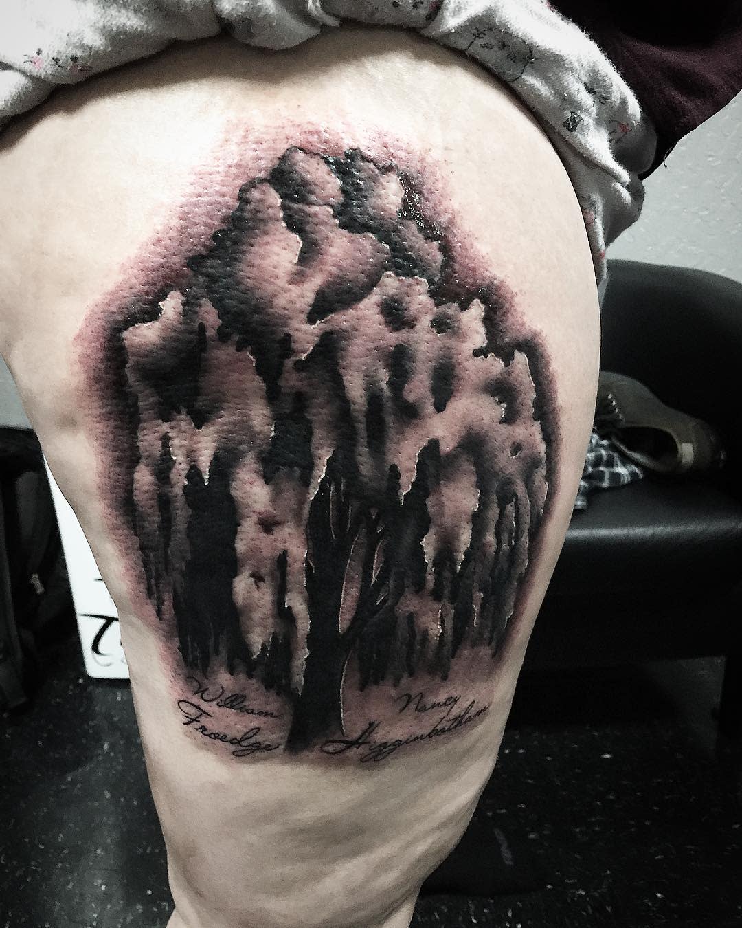 Tattoo of a dark, abstract willow tree design on an upper thigh