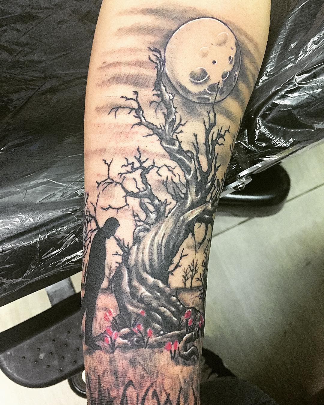 Tattoo of an individual under a twisted weeping willow with a large moon and barren branches