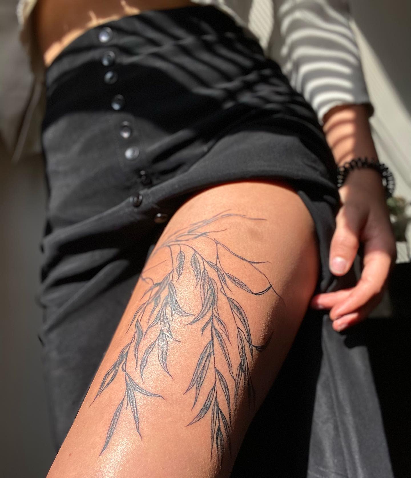 Tattoo of willow tree leaves on thigh