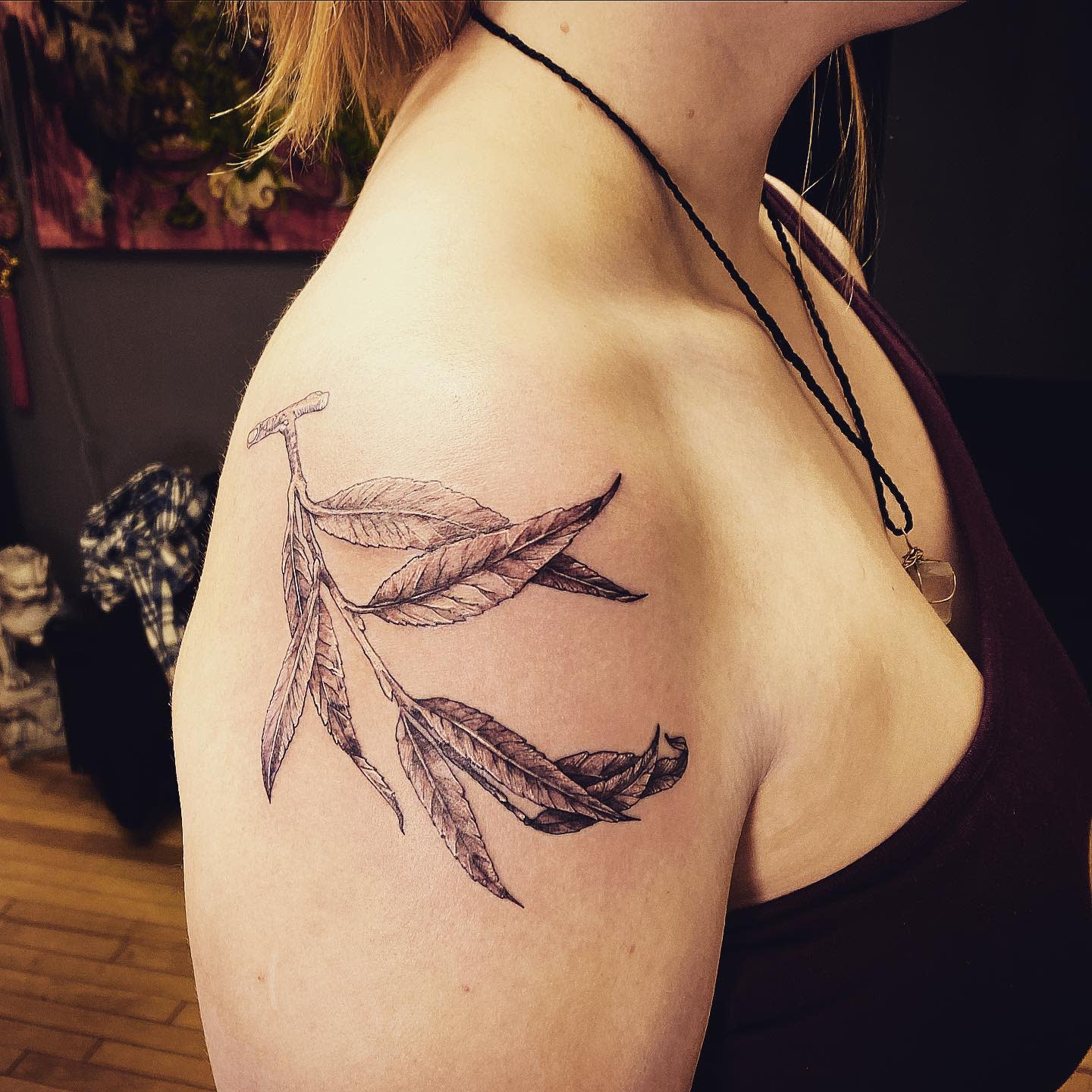 Tattoo of a branch with willow tree leaves on an upper arm