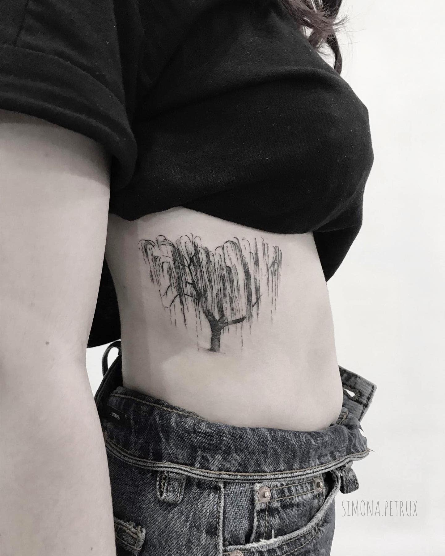 Black-and-white tattoo of a willow tree on a side torso