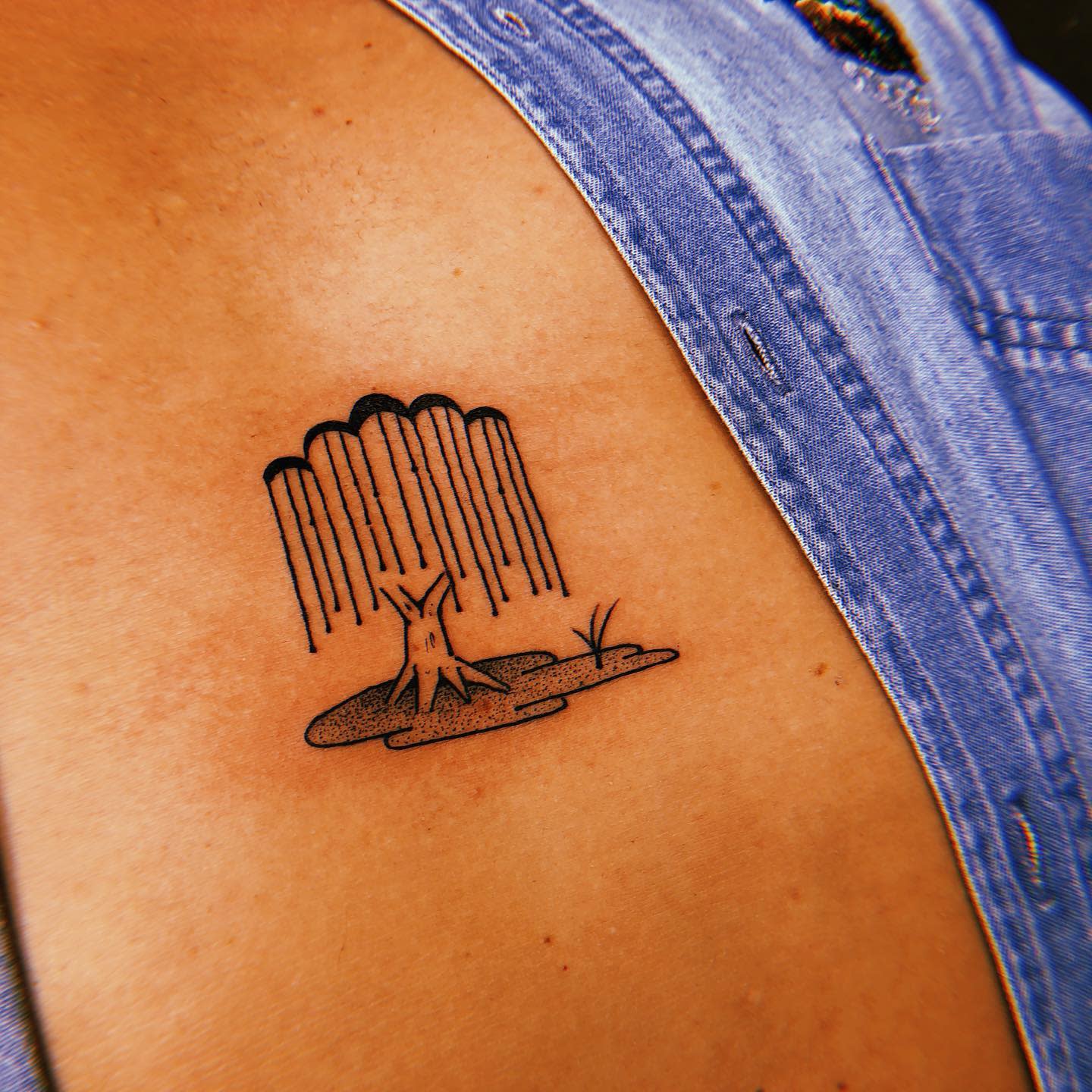 A tattoo of a tree stump with a waterfall in the background on skin
