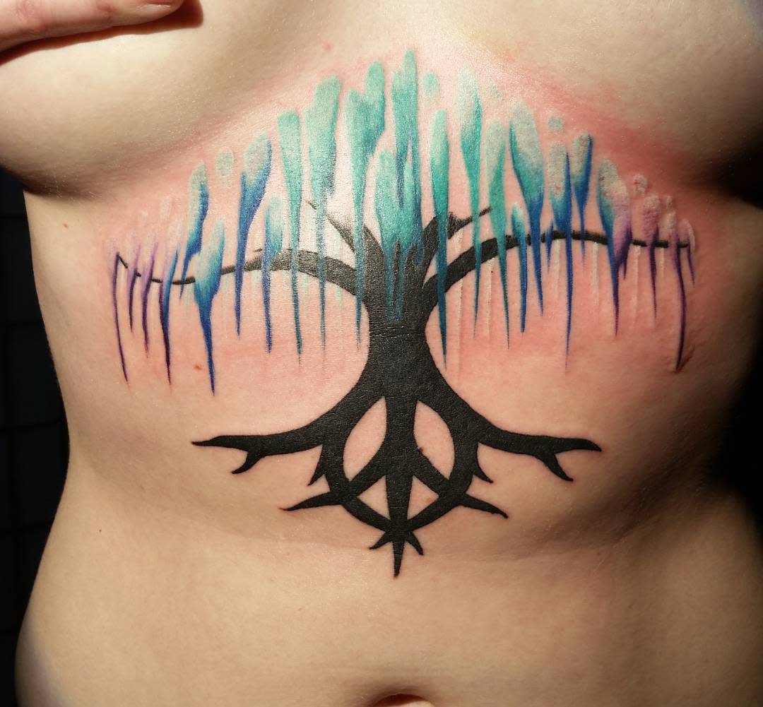 Tattoo of a willow tree with roots and branches extending on the chest