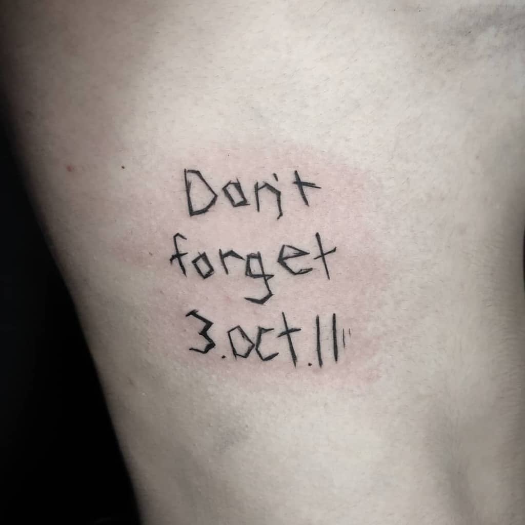Fullmetal Alchemist tattoo of the phrase "Don't forget 3. Oct. 11" in a handwritten style, referencing a key date from the series