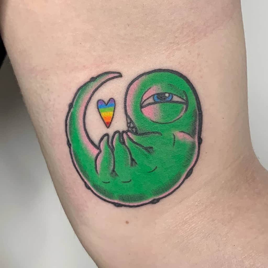 Fullmetal Alchemist tattoo of Envy’s true form, depicted as a green, serpentine creature with a single eye, a rainbow heart