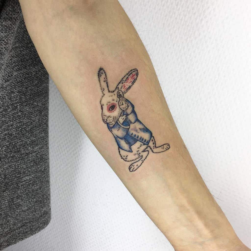 Colorful tattoo of the White Rabbit from Alice in Wonderland, wearing a blue jacket and holding a pocket watch
