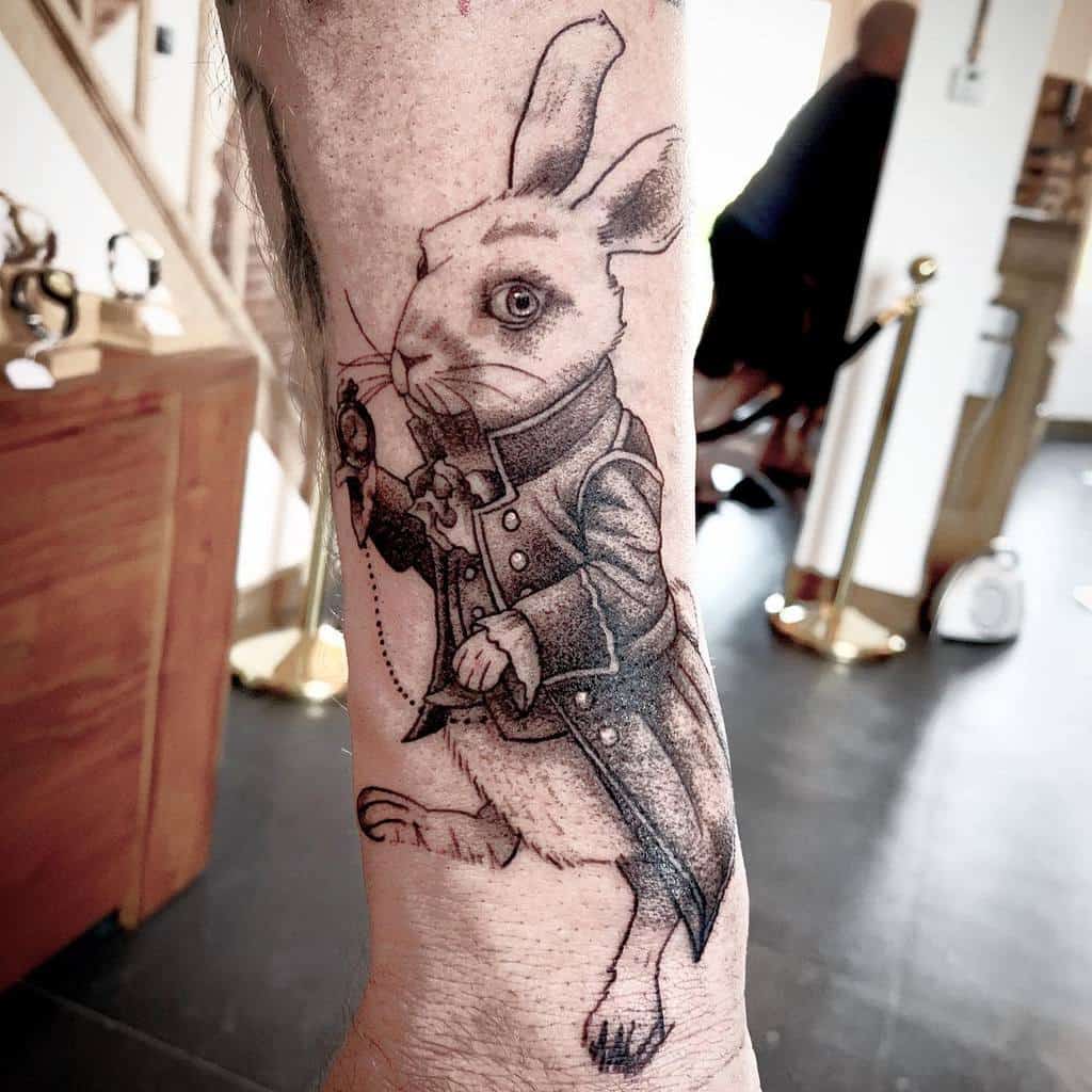 Black and white tattoo of the White Rabbit from Alice in Wonderland, wearing a coat and holding a pocket watch