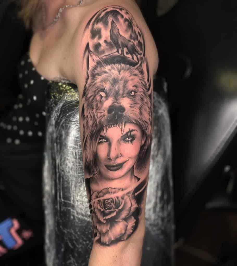 Detailed arm tattoo featuring a woman wearing a wolf head, a howling wolf in front of a full moon, and a rose at the forearm, all in black and grey shading