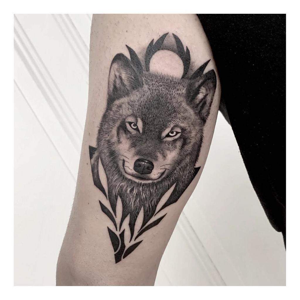 Tattoo of a wolf's head with geometric shapes and a moon on an arm