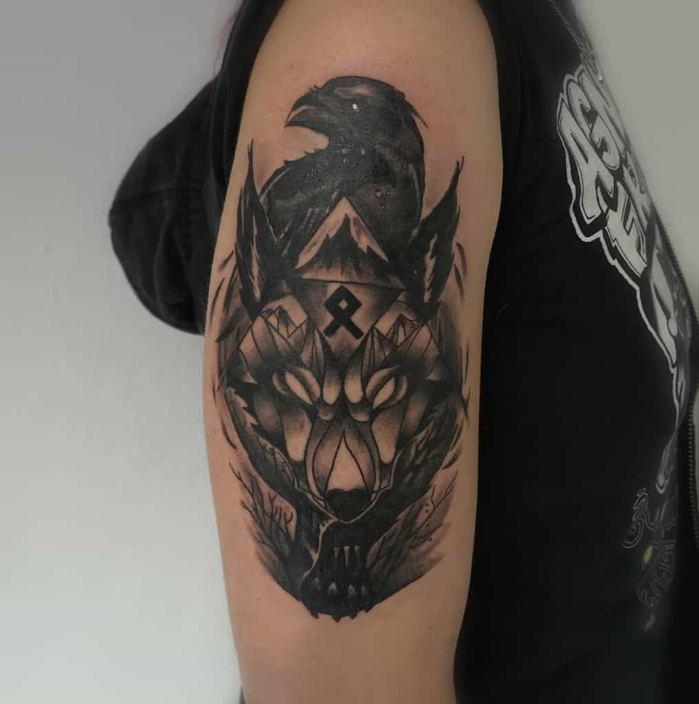 Upper arm tattoo featuring a wolf with glowing eyes, a raven perched above, trees, and mountains in a dark, mystical design