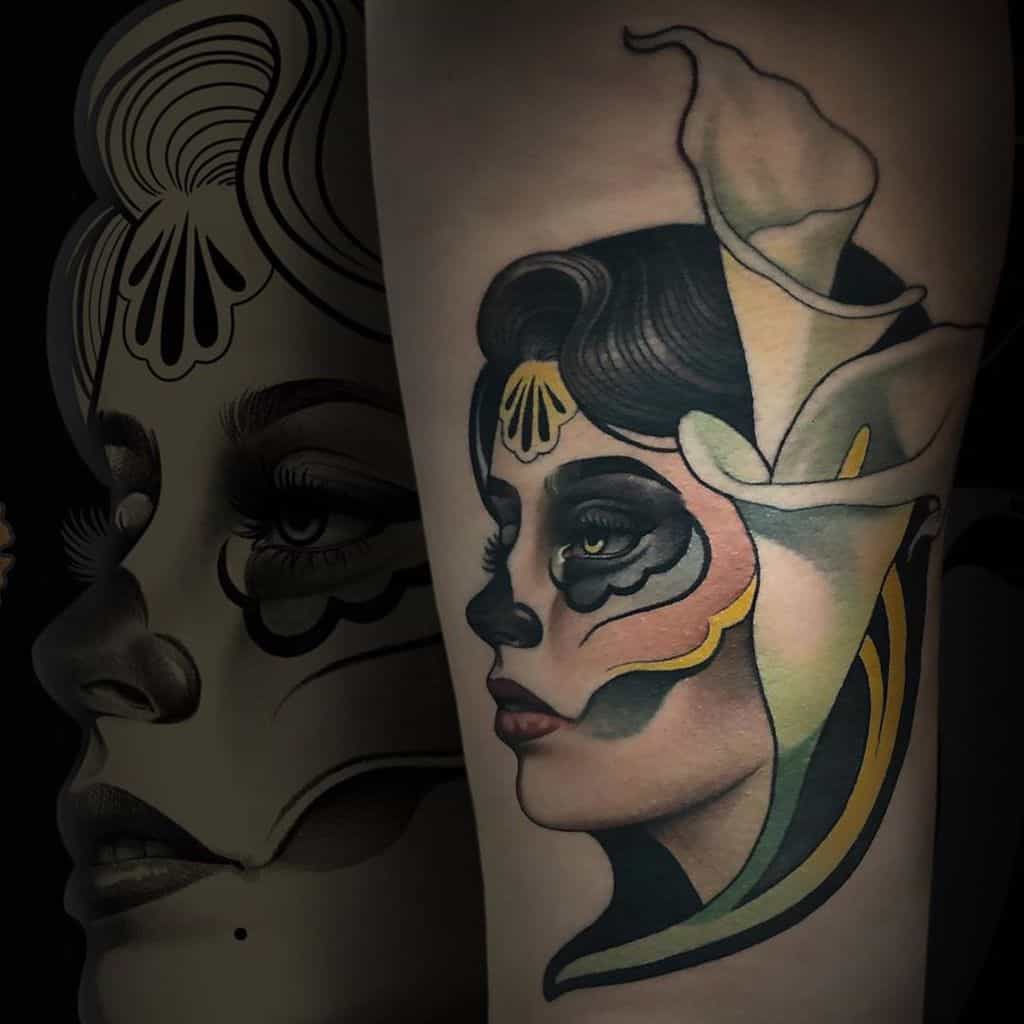Art Nouveau tattoo of a woman with black and gold face paint, adorned with a calla lily, blending elegance and mystery
