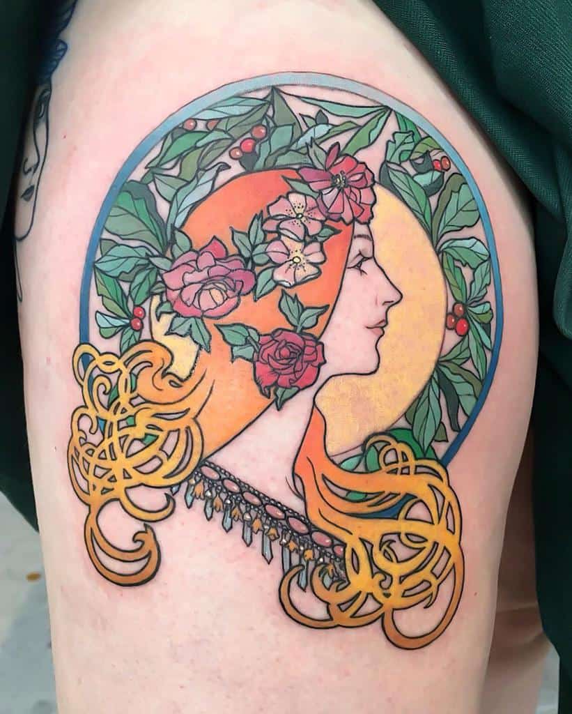Art Nouveau tattoo of a woman with flowing golden hair, floral headpiece, and a circular frame of lush green leaves and berries
