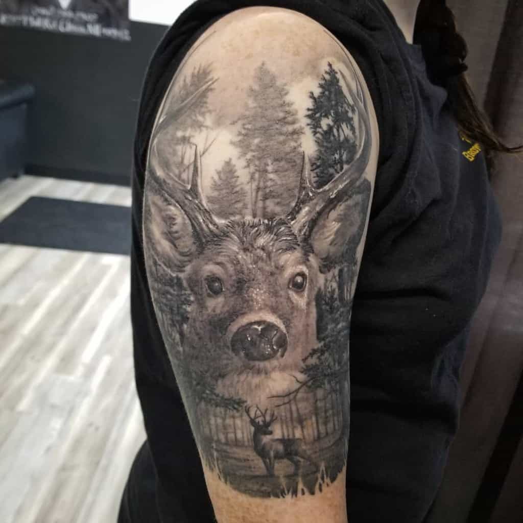 Arm tattoo of a deer in a forest scene on an upper arm