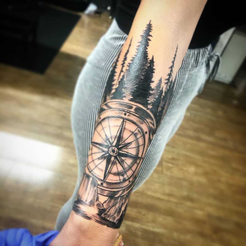 Forearm tattoo of compass and trees on woman
