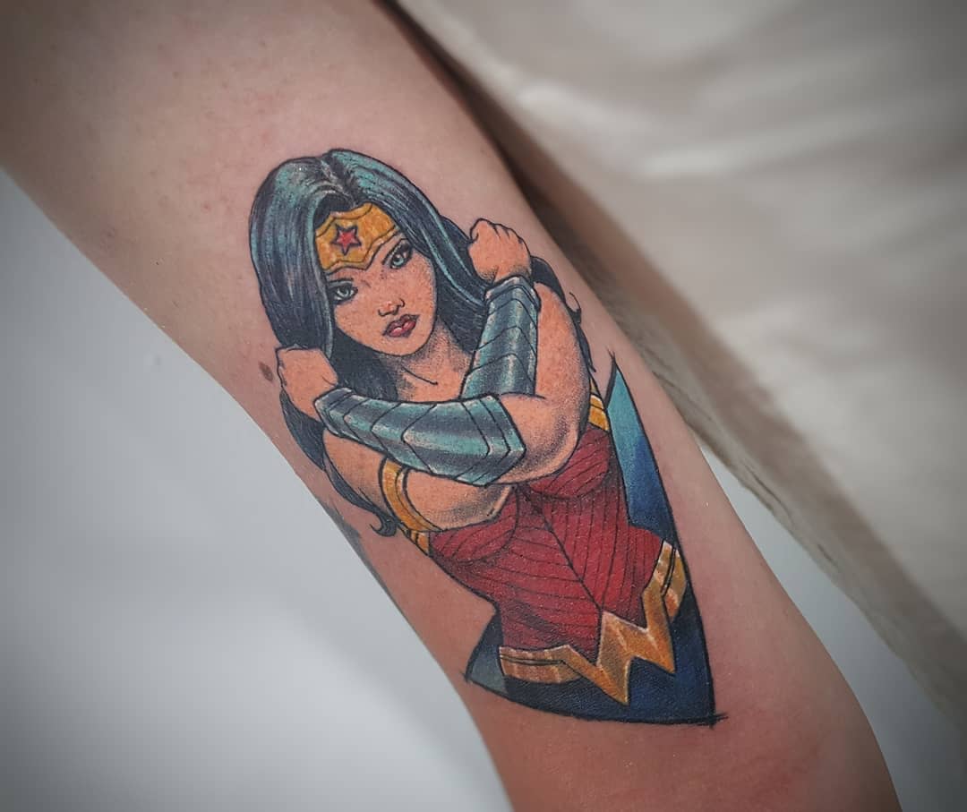 Colorful tattoo of Wonder Woman crossing her arms in a defensive pose, inspired by comic book art