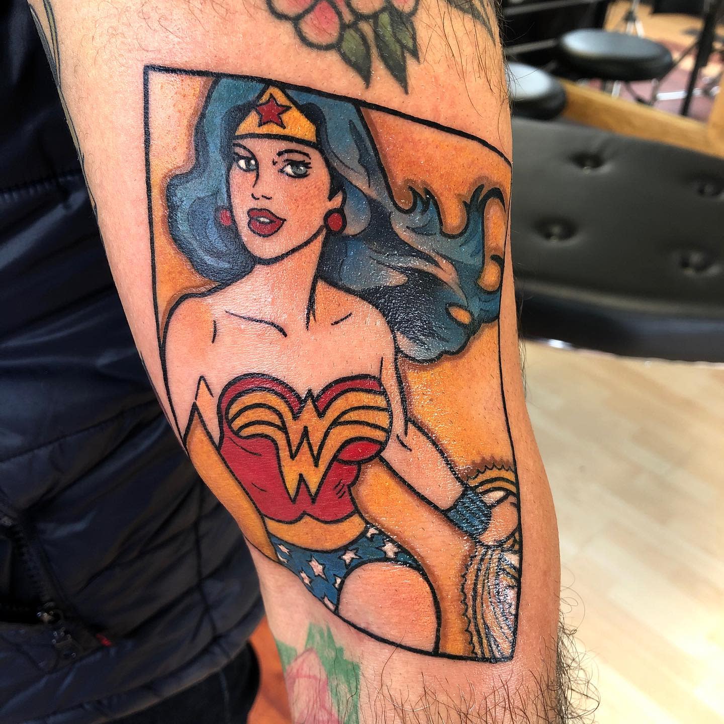 Vibrant tattoo of Wonder Woman in classic comic style, holding her lasso with flowing hair