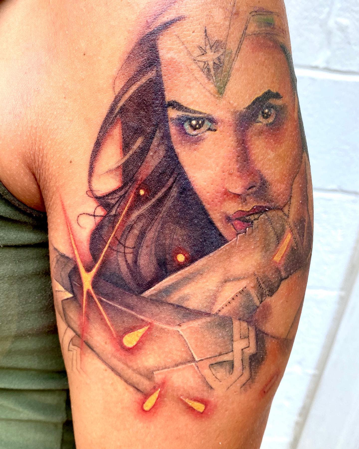 Intense realistic Wonder Woman tattoo, focused on her determined gaze with detailed shading and glowing effects