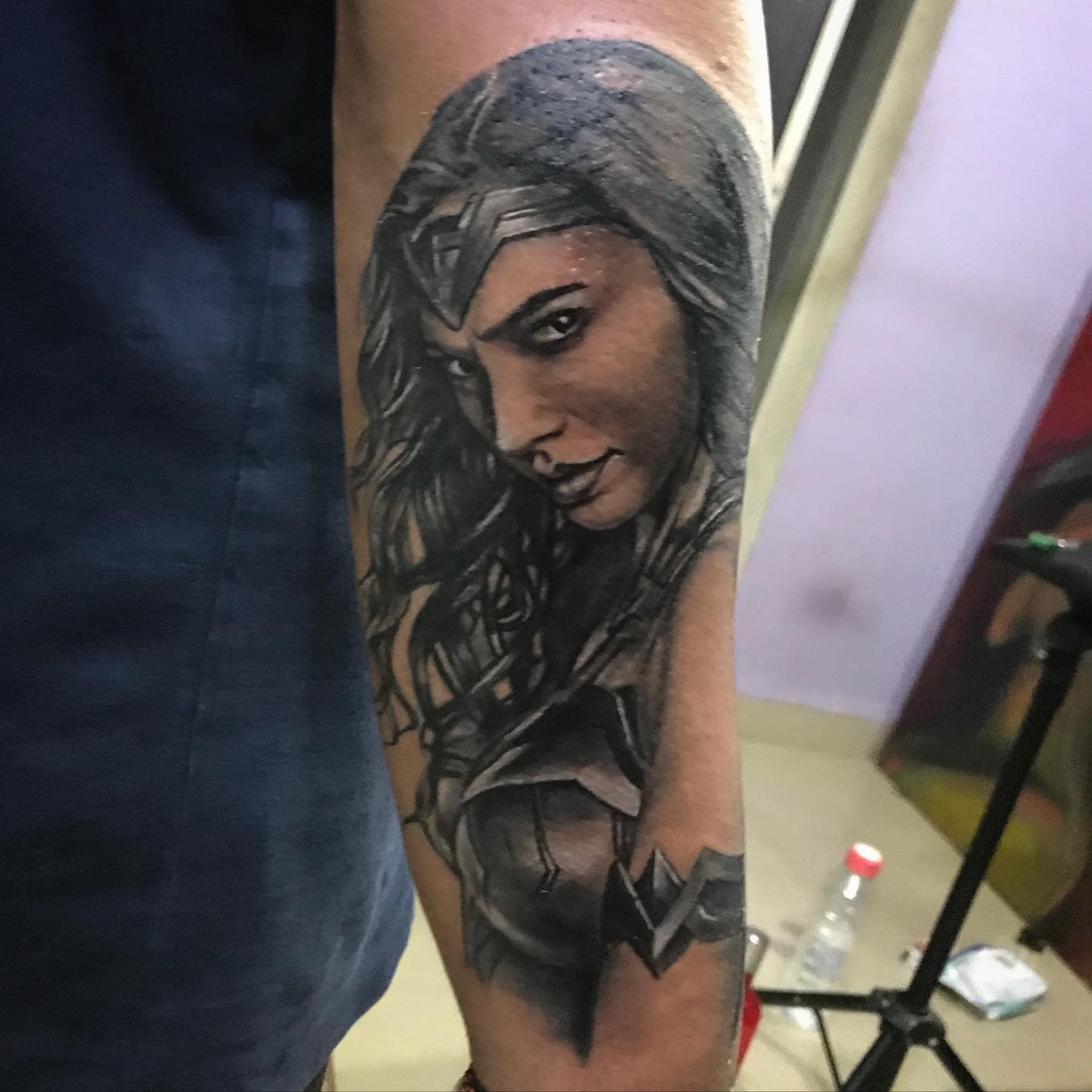 Detailed black and gray tattoo of Wonder Woman with an intense gaze, emphasizing her strong features