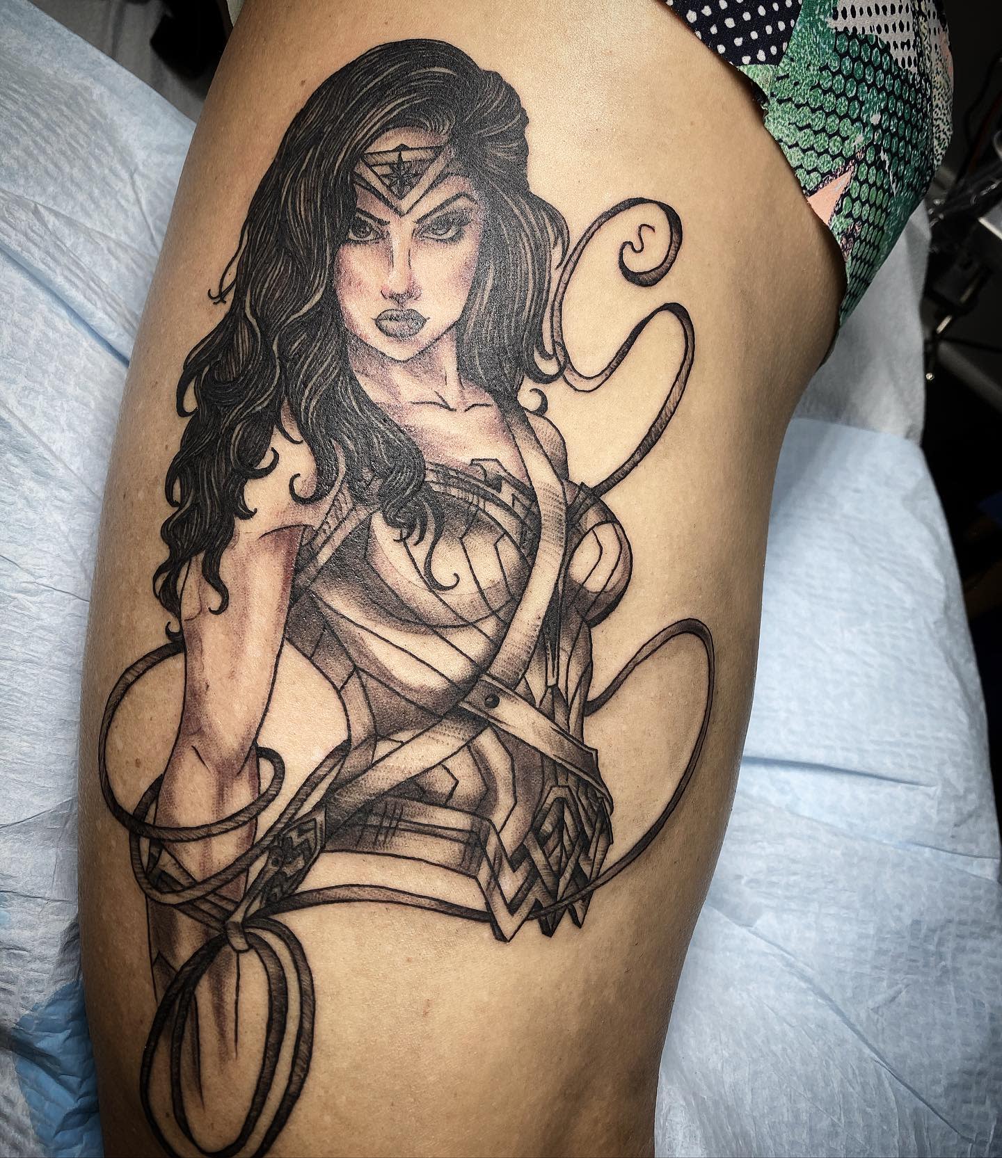Tattoo of Wonder Woman in a striking black and gray style, emphasizing her strength and warrior spirit