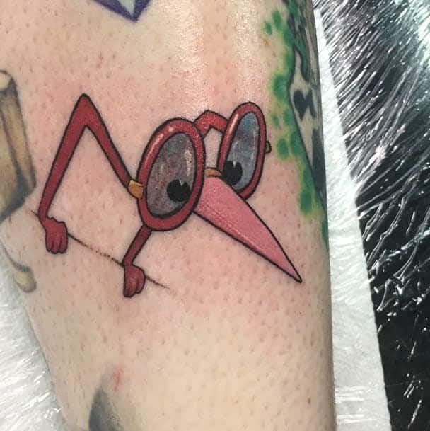 A playful tattoo of the Dodo from Alice in Wonderland, with oversized glasses and a long nose, in a cartoonish style