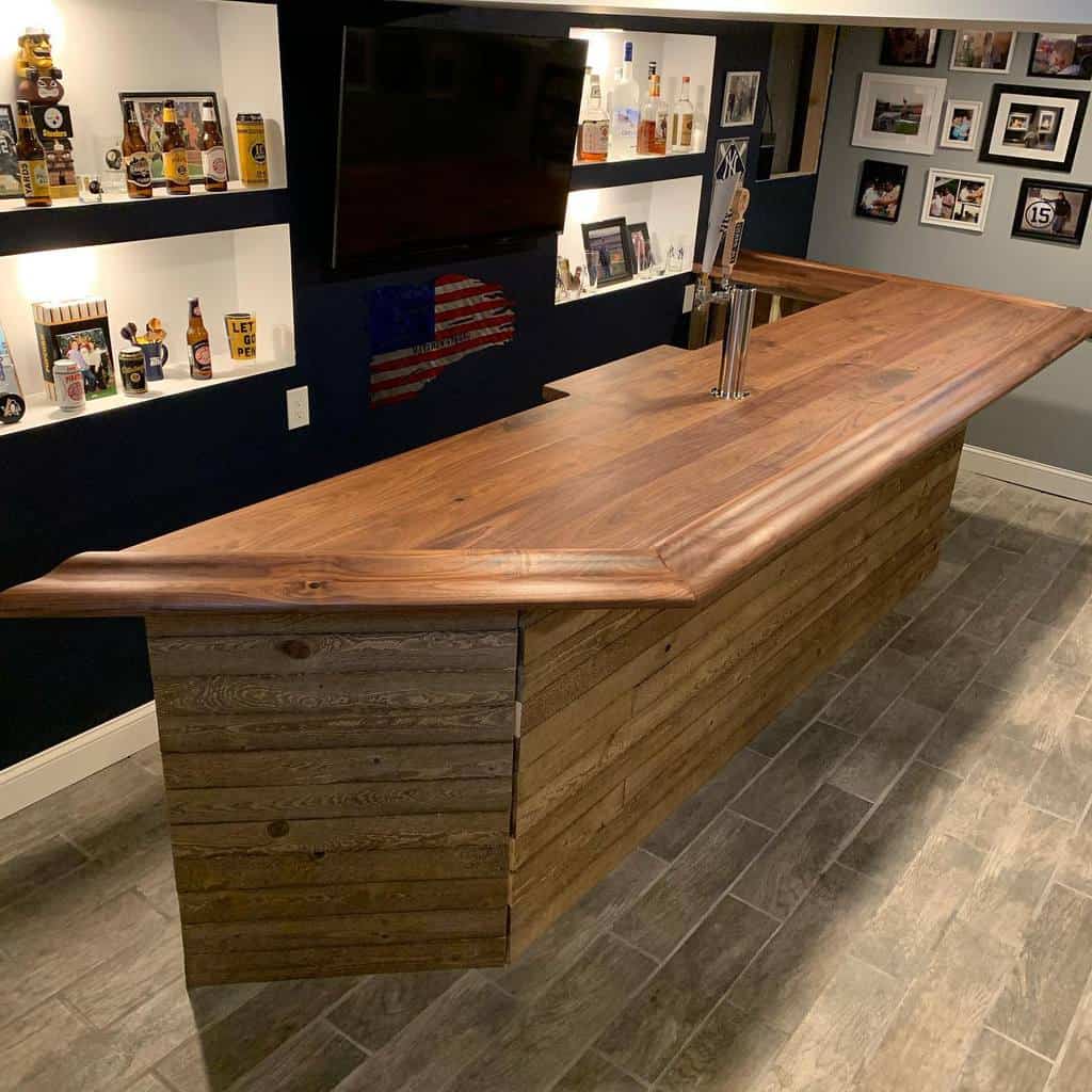 Simple wood basement bar with a natural wood countertop, built-in shelves, and beer taps.
