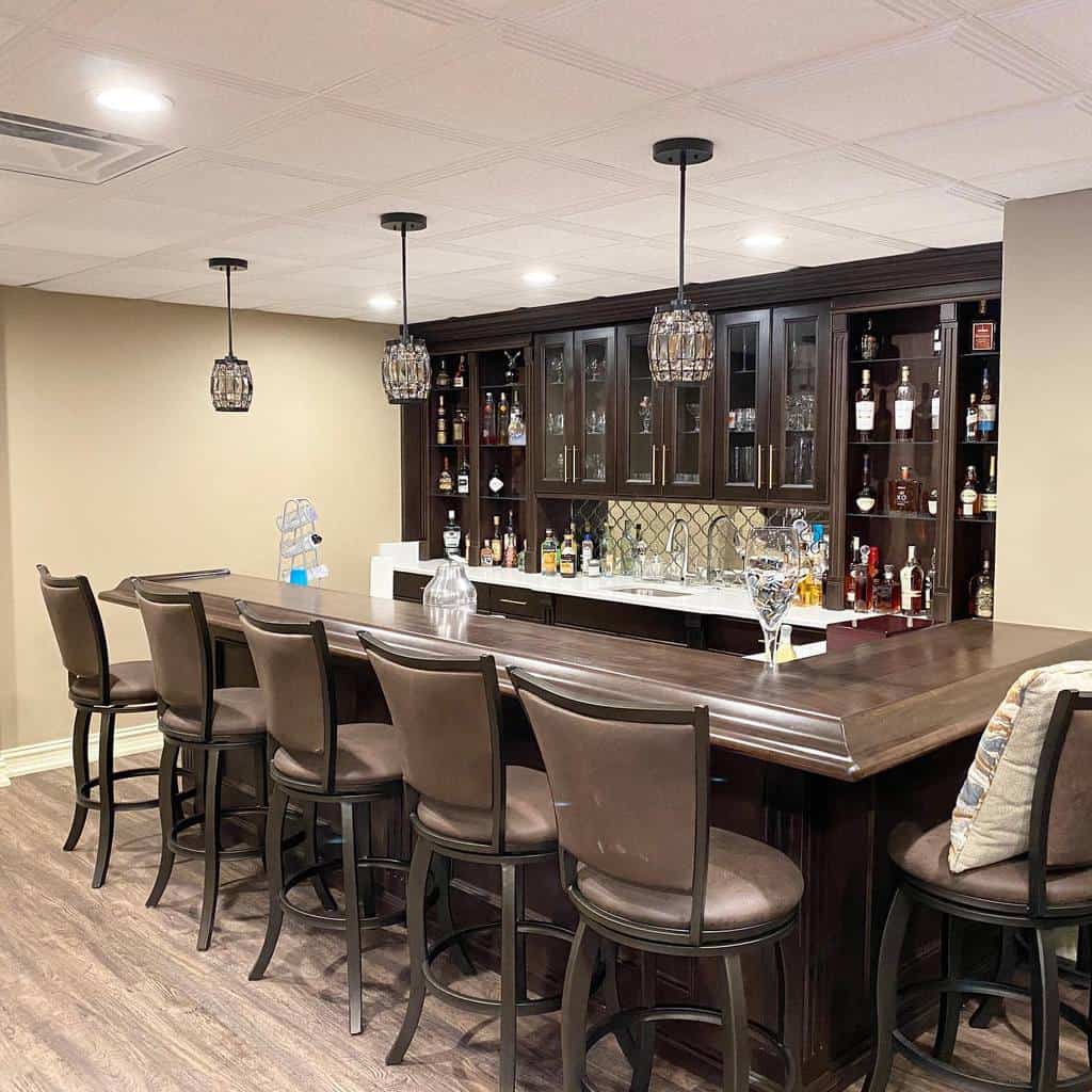 Traditional wood basement bar with leather bar stools, glass-front cabinetry, and pendant lighting.