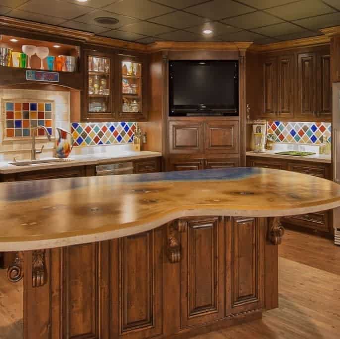 A traditional wood wet bar with colorful tile backsplash, a curved countertop, and built-in cabinetry.
