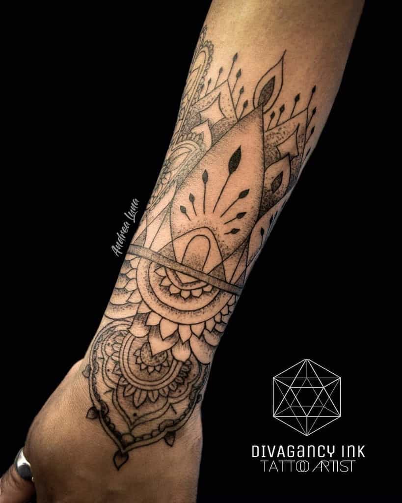 Chandelier-style forearm tattoo featuring intricate mandala patterns, ornamental linework, delicate dot shading, and a pendant-like design