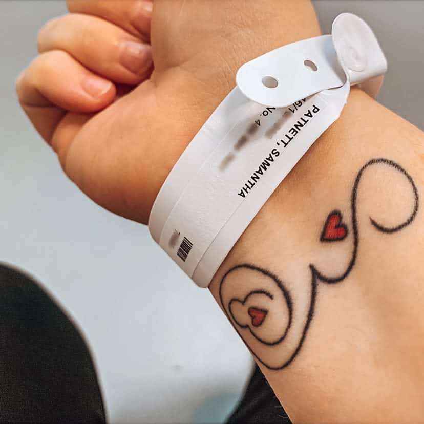 A close-up of a tattoo featuring red hearts and a black swirl pattern