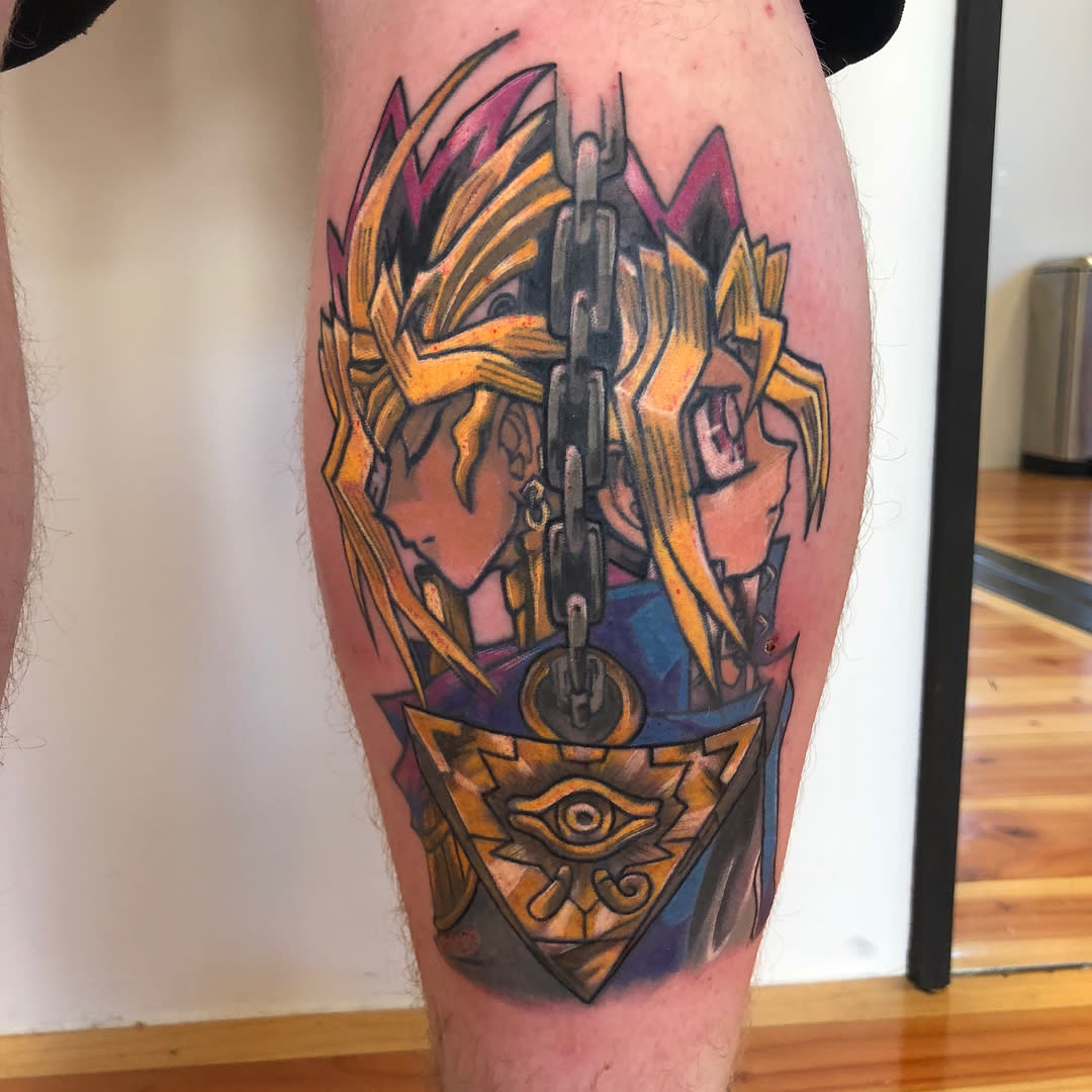 Tattoo of an anime-style character with a chain and pyramid on the back of the leg