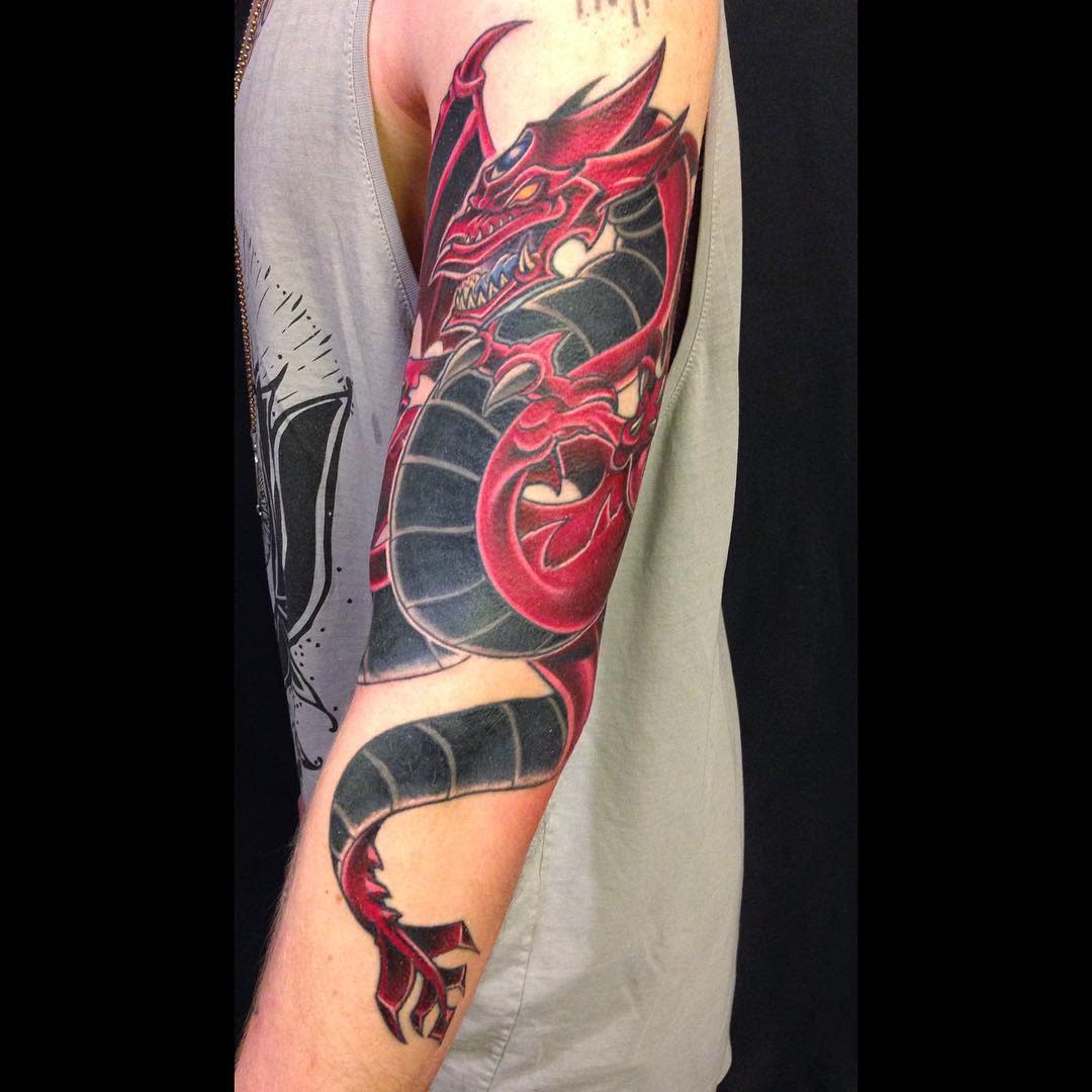 A detailed red and black dragon tattoo on an upper arm
