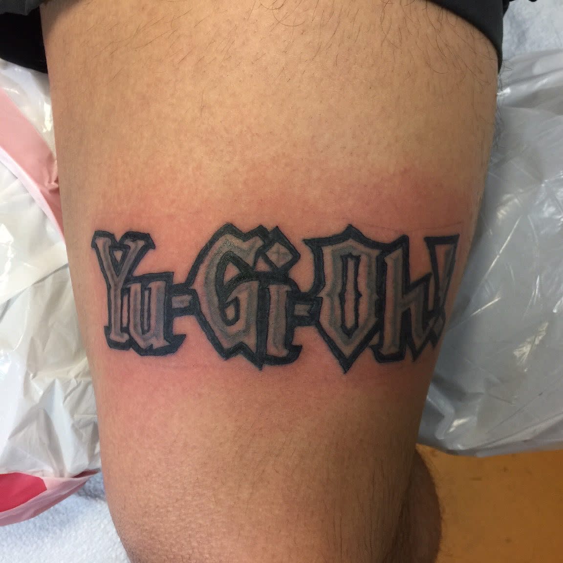 Tattoo of the "Yu-Gi-Oh!" logo on a thigh